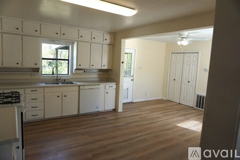 A kitchen with white cabinets and a window.