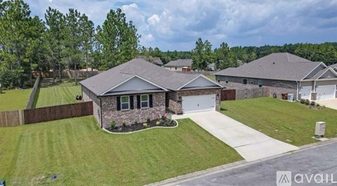 A house with a garage is surrounded by a well-maintained lawn and a wooden fence.