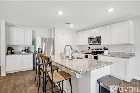 A kitchen with white cabinets and a granite countertop.