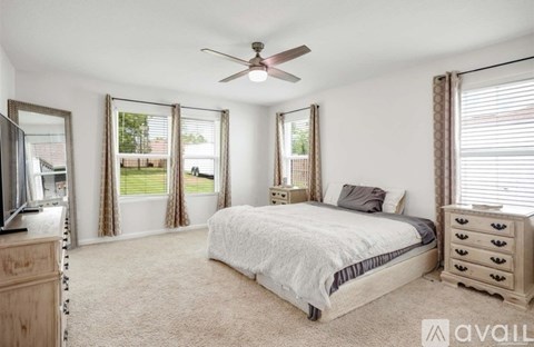 A bedroom with a large bed, a dresser, and a ceiling fan.