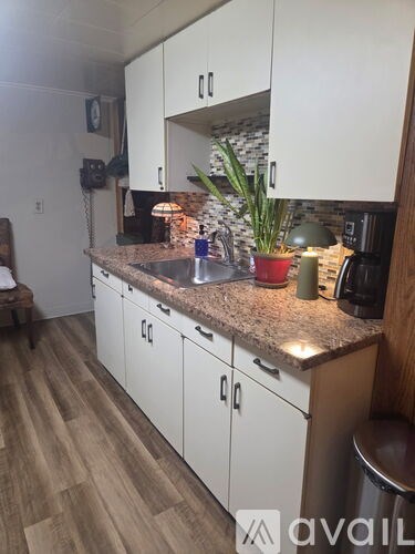 A kitchen with white cabinets and a granite countertop.