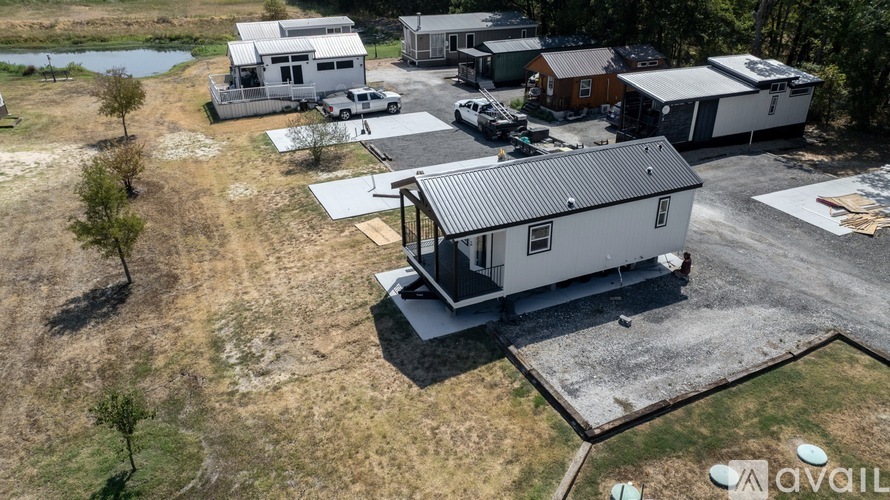 A house with a metal roof is surrounded by other houses and vehicles.