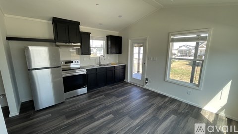 A kitchen with a white refrigerator, black cabinets, and a wooden floor.