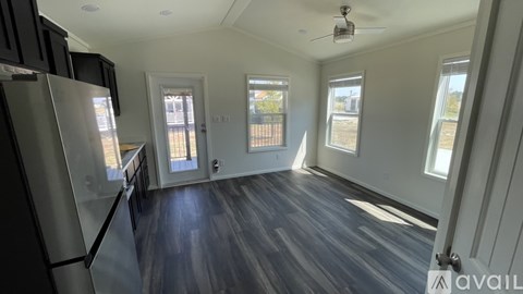 A kitchen with a refrigerator, cabinets, and a ceiling fan.