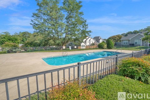 A pool surrounded by a fence with a house in the background.