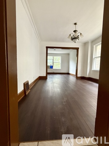 A long hallway with wood floors and a chandelier.
