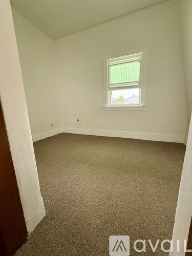 A room with a carpeted floor and a window with a green curtain.