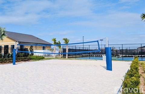 A tennis court with a blue fence and a building in the background.