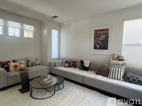 A living room with a grey couch, a coffee table, and a painting on the wall.