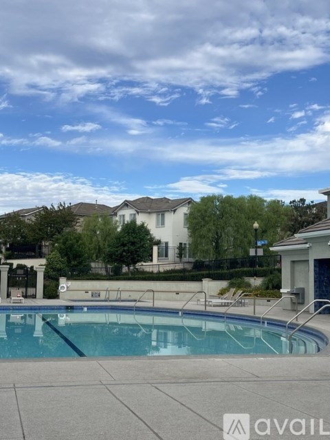 A pool in front of a house with a blue sky and clouds.