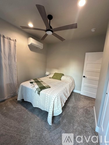 A bedroom with a bed, a ceiling fan, and a window with curtains.