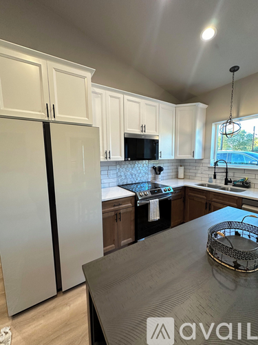 A kitchen with white cabinets and a black refrigerator.