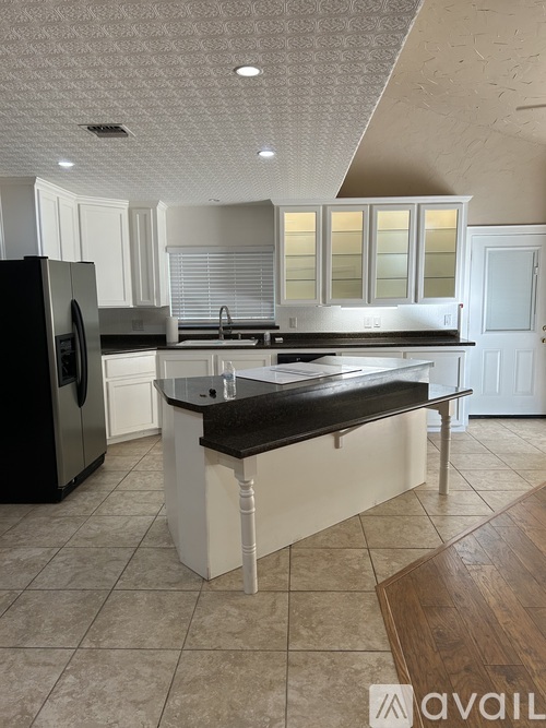 A kitchen with a black refrigerator and white cabinets.