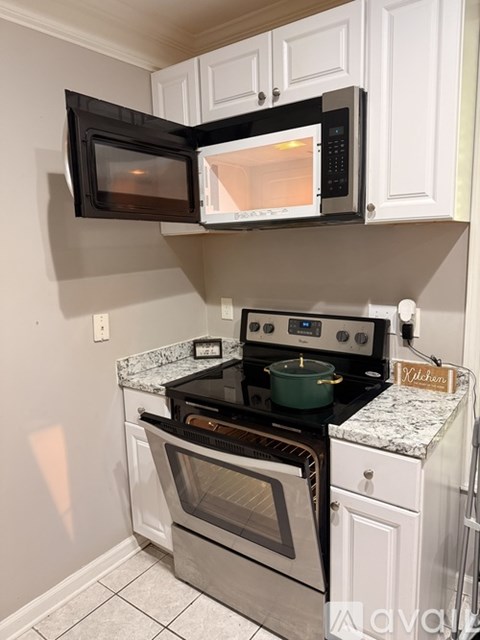 A black microwave oven is mounted above a stove top oven in a kitchen.