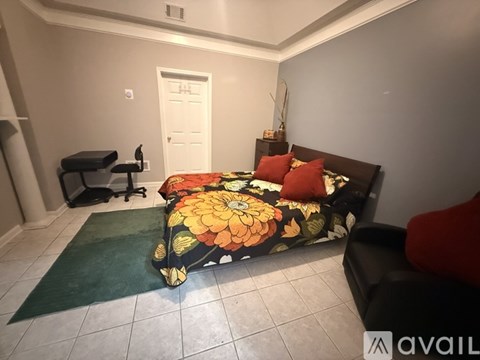 A bedroom with a bed, a chair, and a rug.