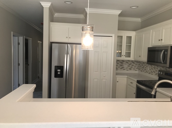 A kitchen with a stainless steel refrigerator and white cabinets.