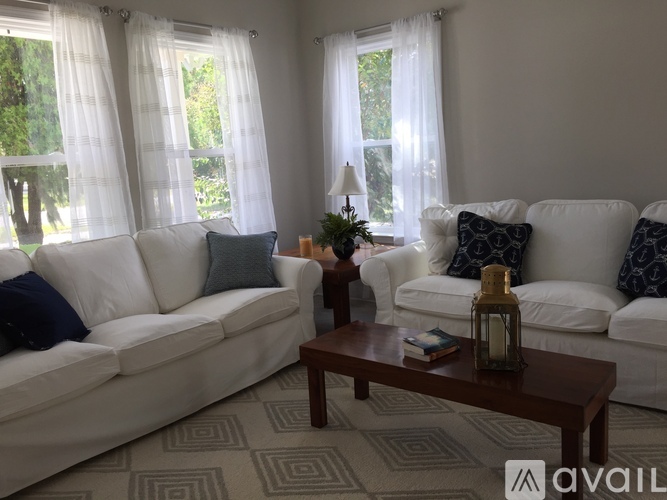 A living room with white couches and a wooden coffee table.