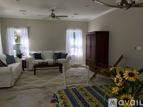 A living room with a white sofa, a wooden cabinet, and a rug with a blue and yellow pattern.