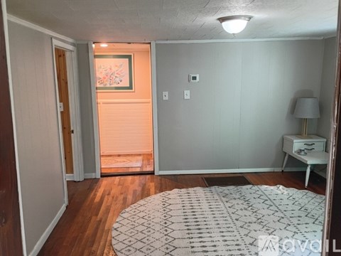 A room with a white rug, a white table, and a wooden floor.