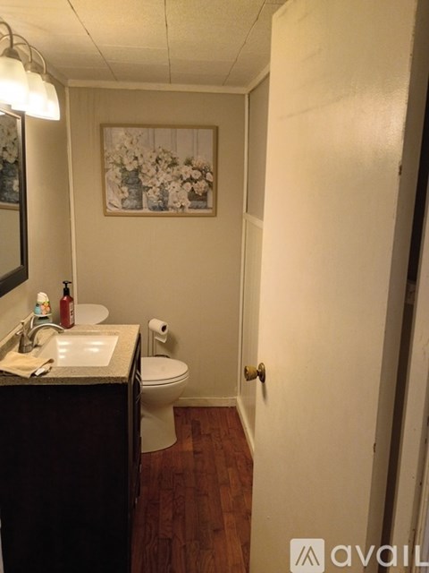 A bathroom with a toilet, sink, and a painting of flowers on the wall.