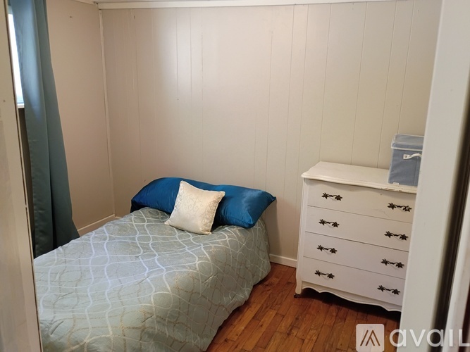 A bedroom with a bed, a dresser, and a window.