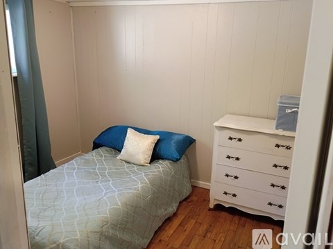 A bedroom with a bed, a dresser, and a window.