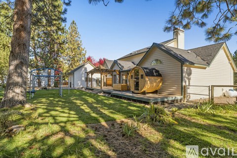 A house with a deck and a tree in front.