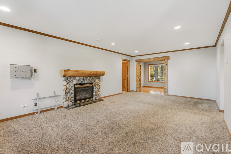 A spacious room with a fireplace and a carpeted floor.