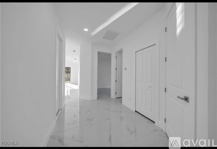 A long hallway with white doors and a marble floor.