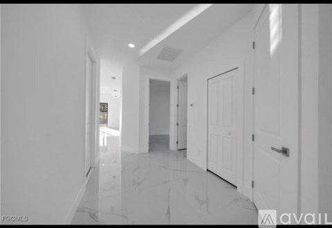 A long hallway with white doors and a marble floor.