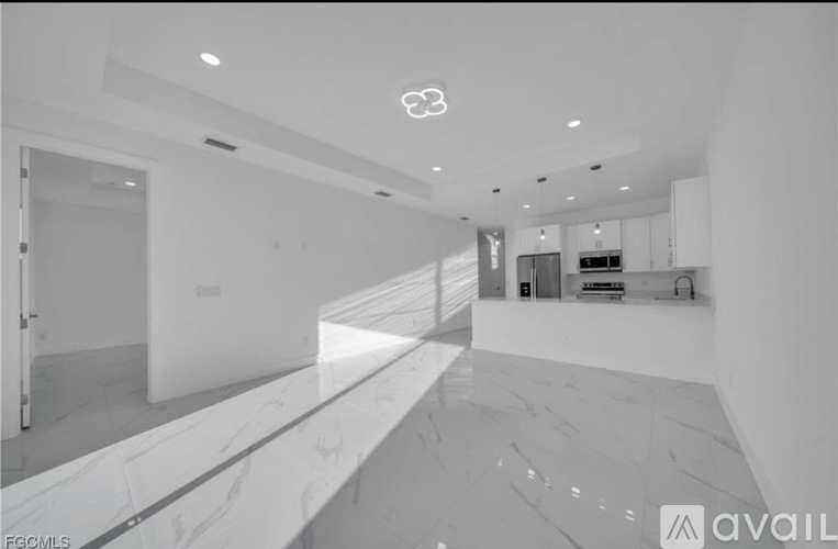 A spacious, white-walled room with marble flooring and a long, reflective mirror on the wall.