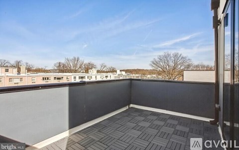 A balcony with a grey floor and a view of buildings and trees.