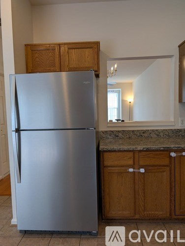 A stainless steel refrigerator in a kitchen with wooden cabinets.