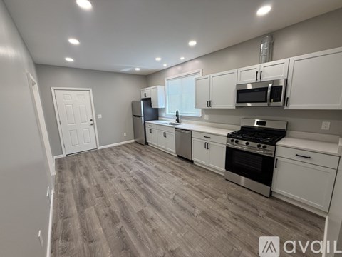 A kitchen with white cabinets and a grey floor.