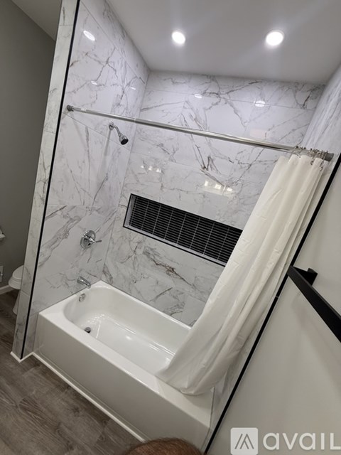A bathroom with a marble wall and a white bathtub.