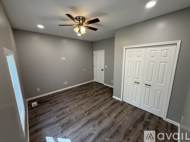 A room with a ceiling fan and wood flooring.