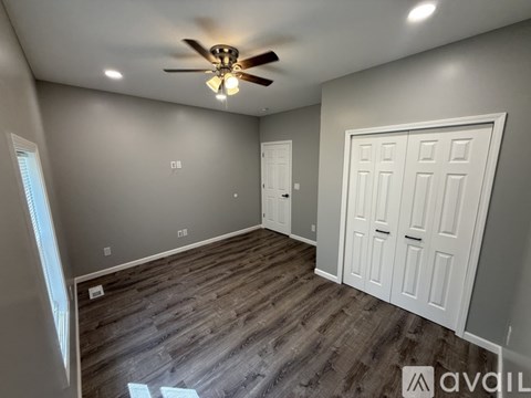 A room with a ceiling fan and wood flooring.