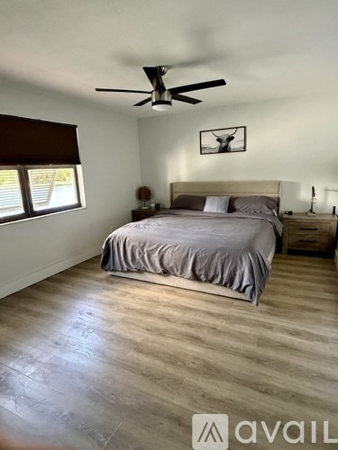 A bedroom with a bed, nightstand, and a ceiling fan.