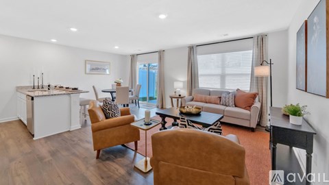 A living room with a brown sofa and a white kitchen area.
