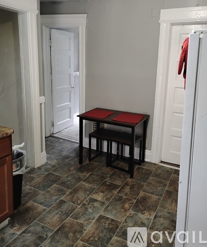 A small table with a red cloth on it sits in a room with a tiled floor.
