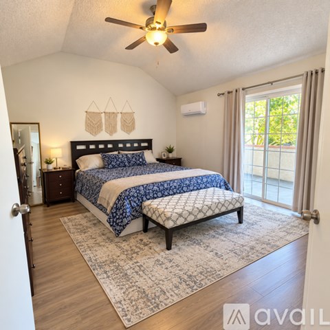 A bedroom with a bed, bench, and a ceiling fan.
