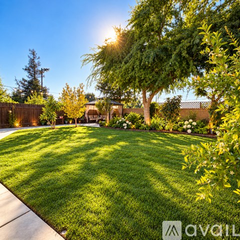 A backyard with a lawn, trees, and a fence.
