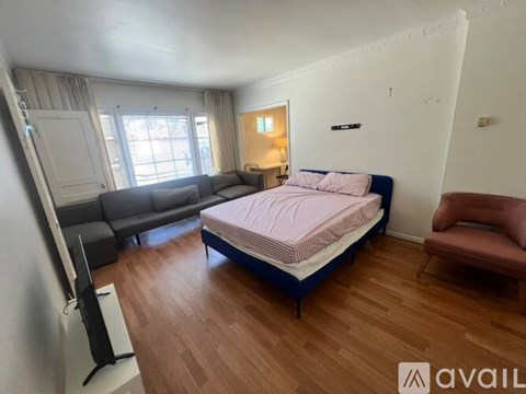 A bedroom with a bed, a couch, and a television.