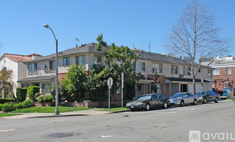 A street view with cars parked on the side of the road and apartment buildings in the background.