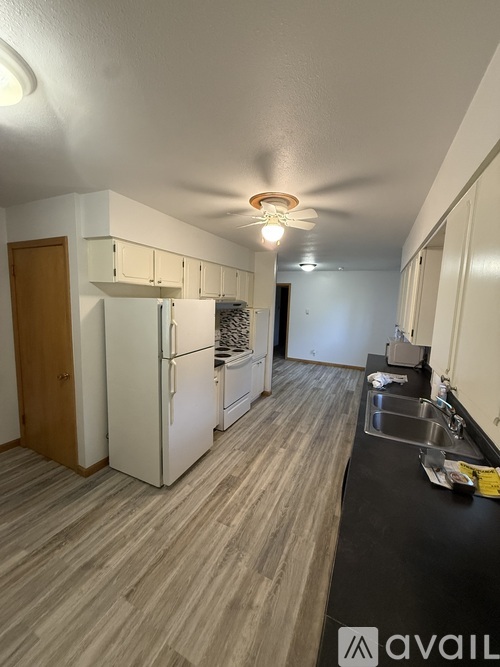 A kitchen with a refrigerator, sink, and cabinets.
