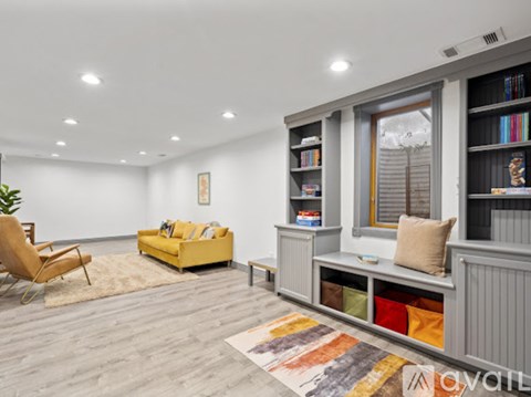 A living room with a yellow sofa and a grey bookshelf.