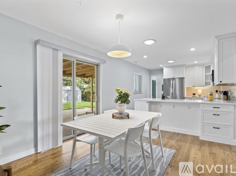 A modern kitchen with white cabinets and a dining table with chairs.