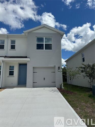 A white two-story house with a garage and a driveway.