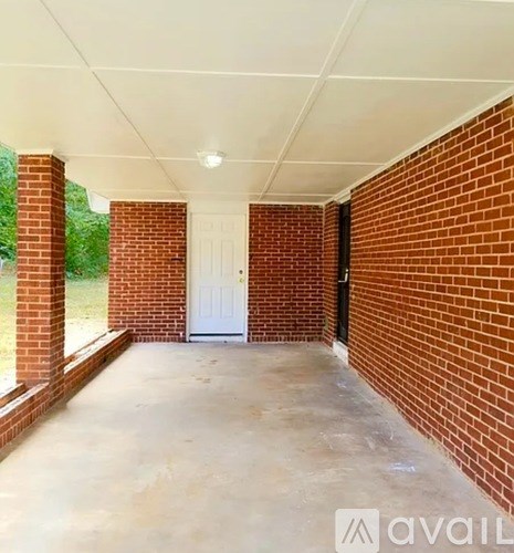 A covered porch with a white door and brick walls.
