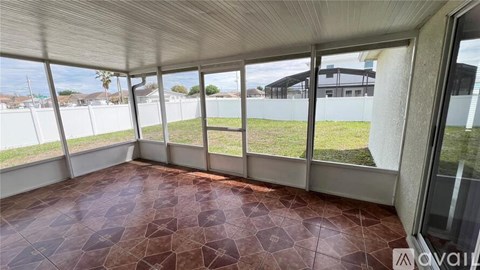 A room with a tiled floor and large windows overlooking a grassy area.